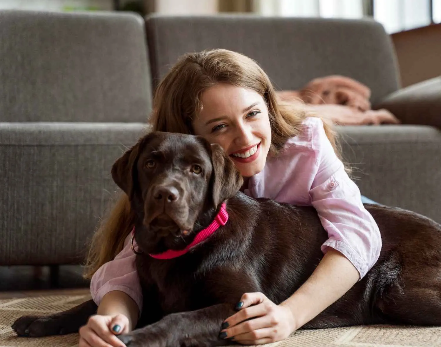 Woman lying on the floor hugging her dog at home.