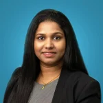Professional woman in black blazer smiling against blue background