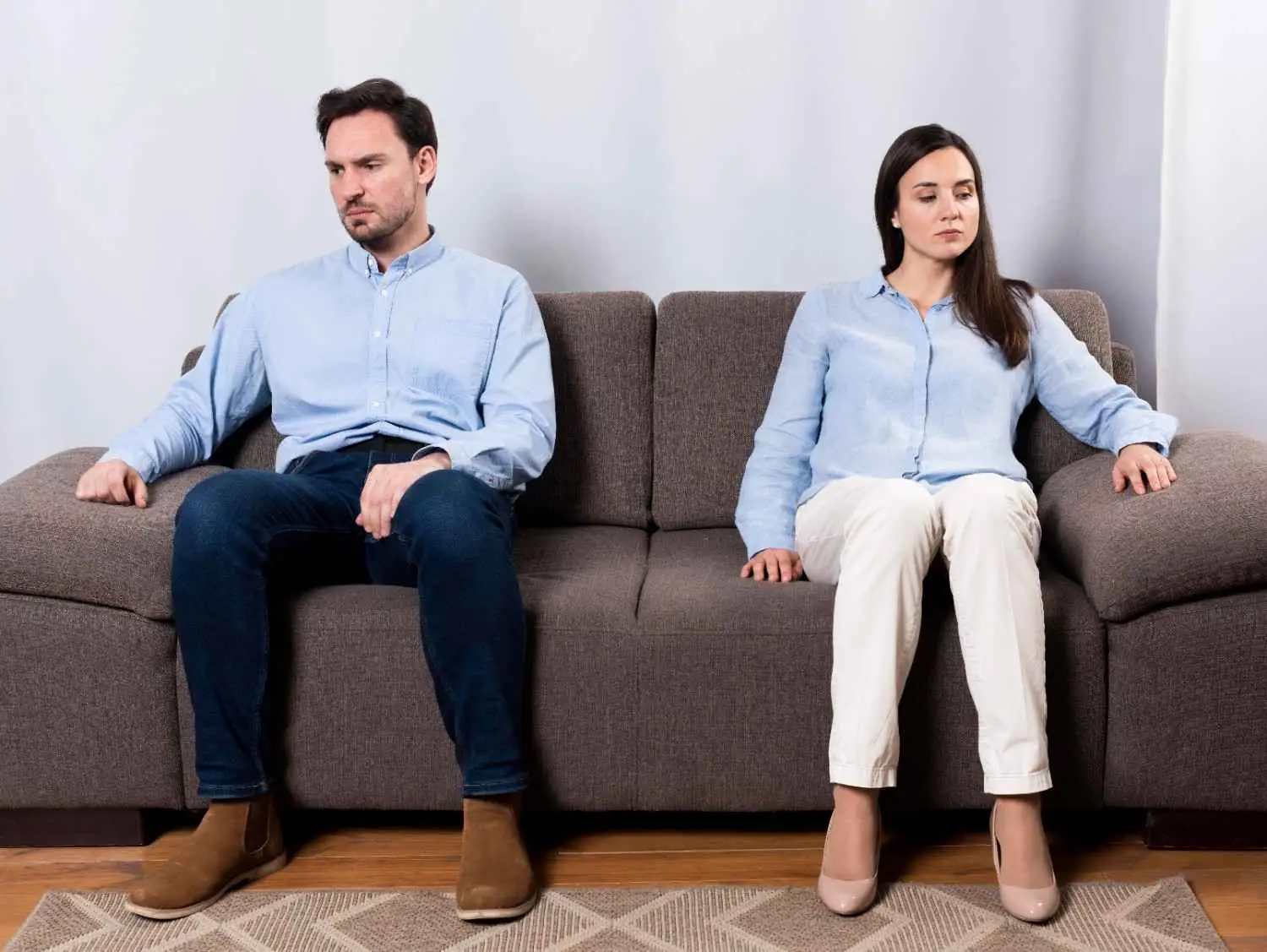 Separated couple sitting apart on sofa, reflecting relationship conflict and separation concerns