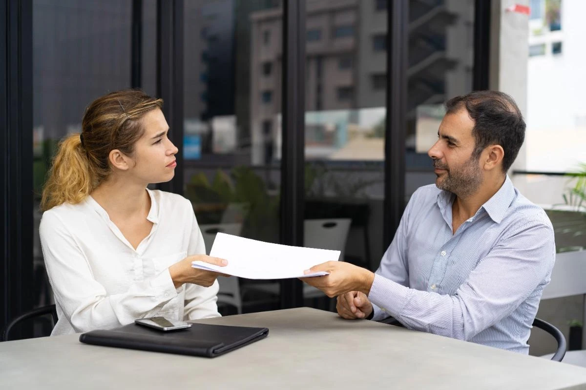 Couple reviewing and exchanging financial documents during separation proceedings.