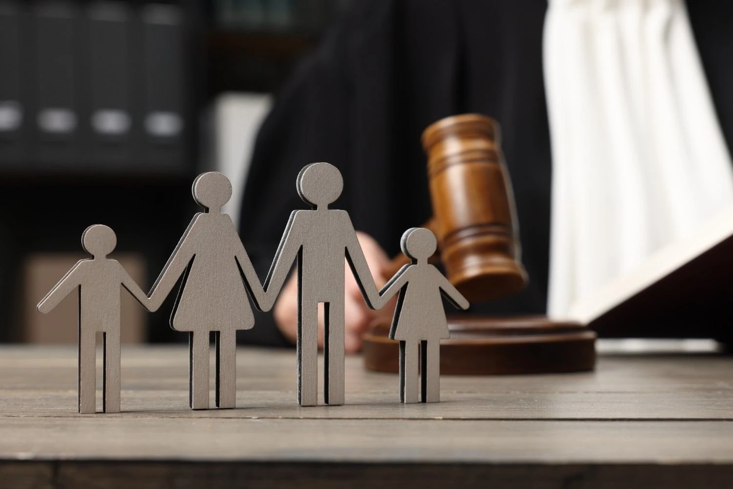 Family represented by wooden figures with a judge’s gavel in the background