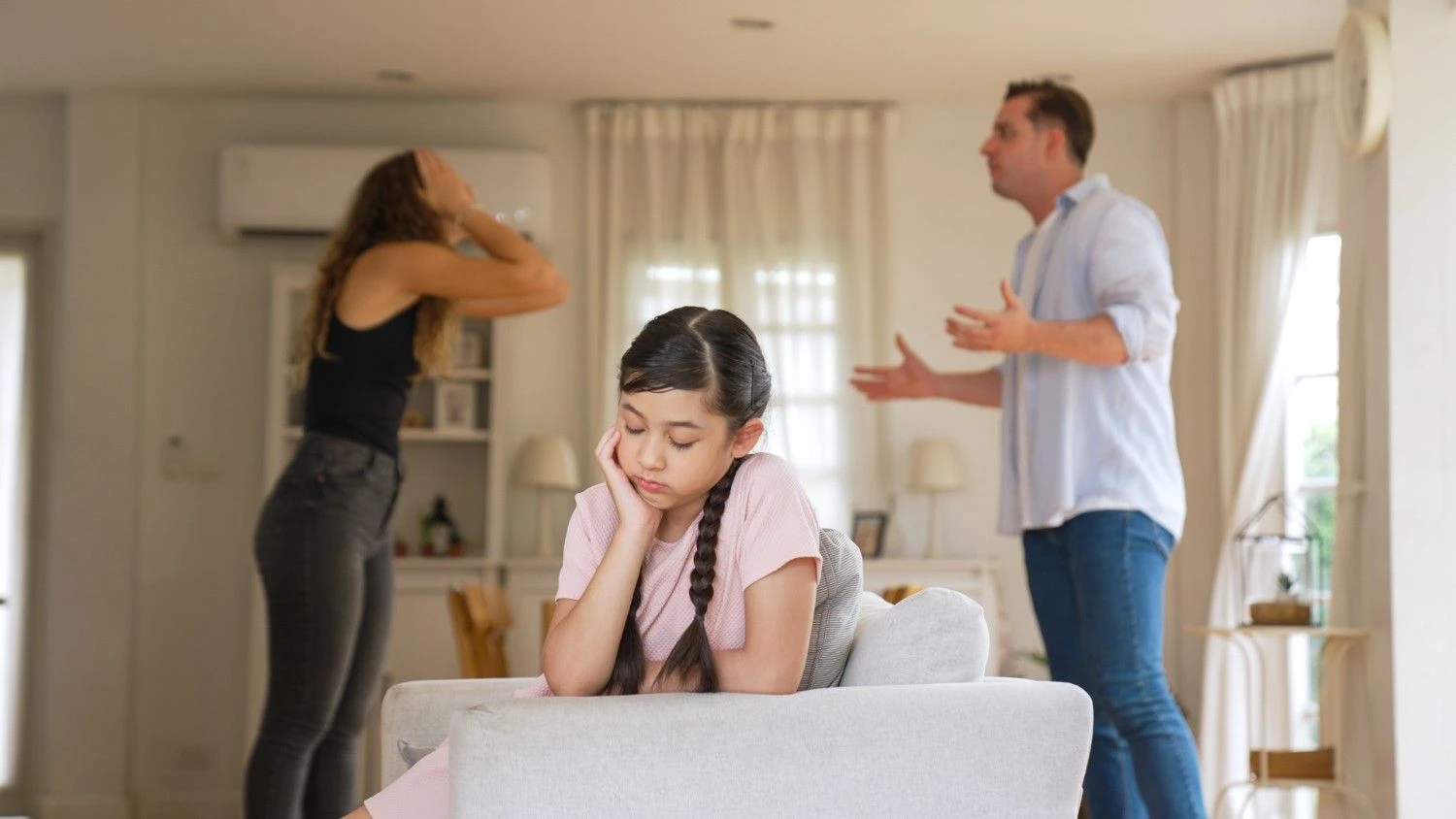 Girl distressed while parents argue in the background